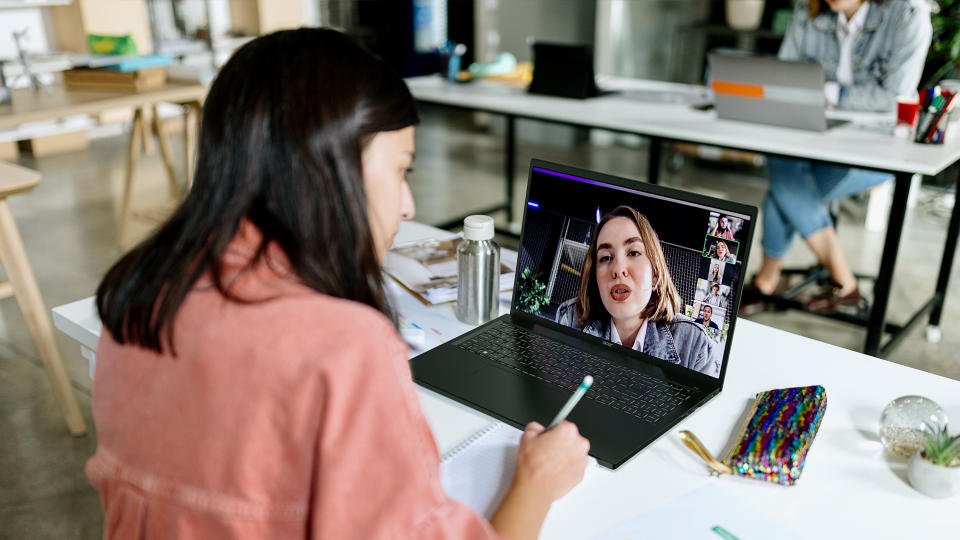 Seseorang duduk di meja, melakukan panggilan video dengan orang lain di Acer Swift Edge 16. Ruang kerja kantor terbuka.