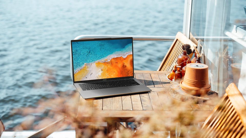 Gambar pemasaran gaya hidup Acer Swift Go 14 duduk di meja luar ruangan tepi pantai.