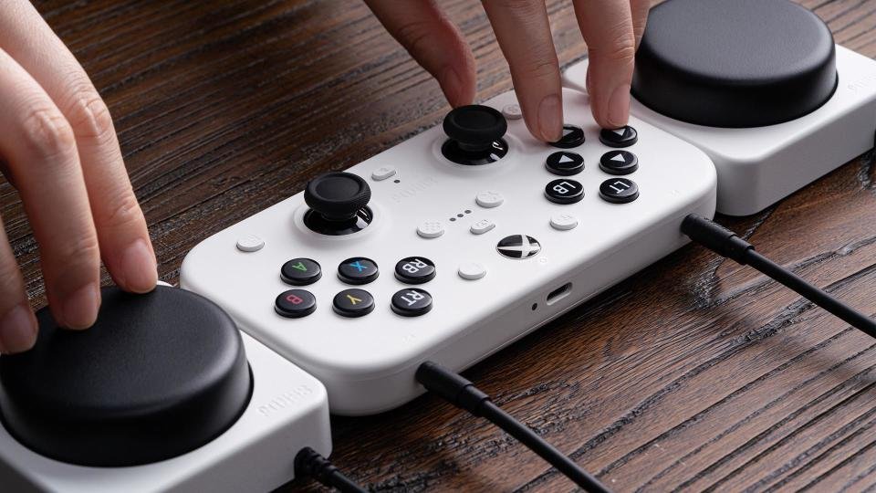 Anda dapat memesan terlebih dahulu Xbox Series X serba digital mulai hari ini - Info Malang Raya Tangan seseorang mengendalikan Pengendali Nirkabel 8BitDo Lite SE 2.4G, yang semua tombolnya berada di permukaan atas. Dua Tombol Super mengapitnya di kedua sisi.
