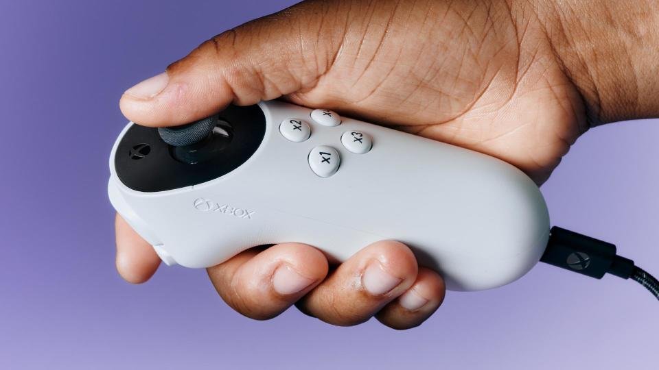 Anda dapat memesan terlebih dahulu Xbox Series X serba digital mulai hari ini - Info Malang Raya Tangan kanan seseorang memegang Joystick Aksesibilitas Xbox di depan latar belakang ungu.