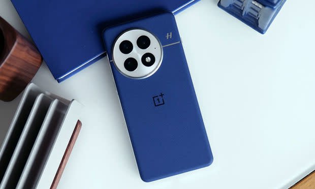 Jangan biarkan AI menjalankan mesin penjual otomatis 3 Gambar bagian belakang OnePlus 13, berwarna biru, di atas meja putih.